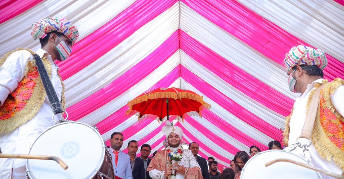 A lively baraat procession with dhol drummers arriving at the wedding venue