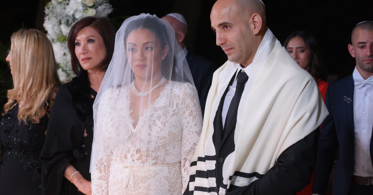 A bride and a groom in a tallit during a Jewish wedding ceremony