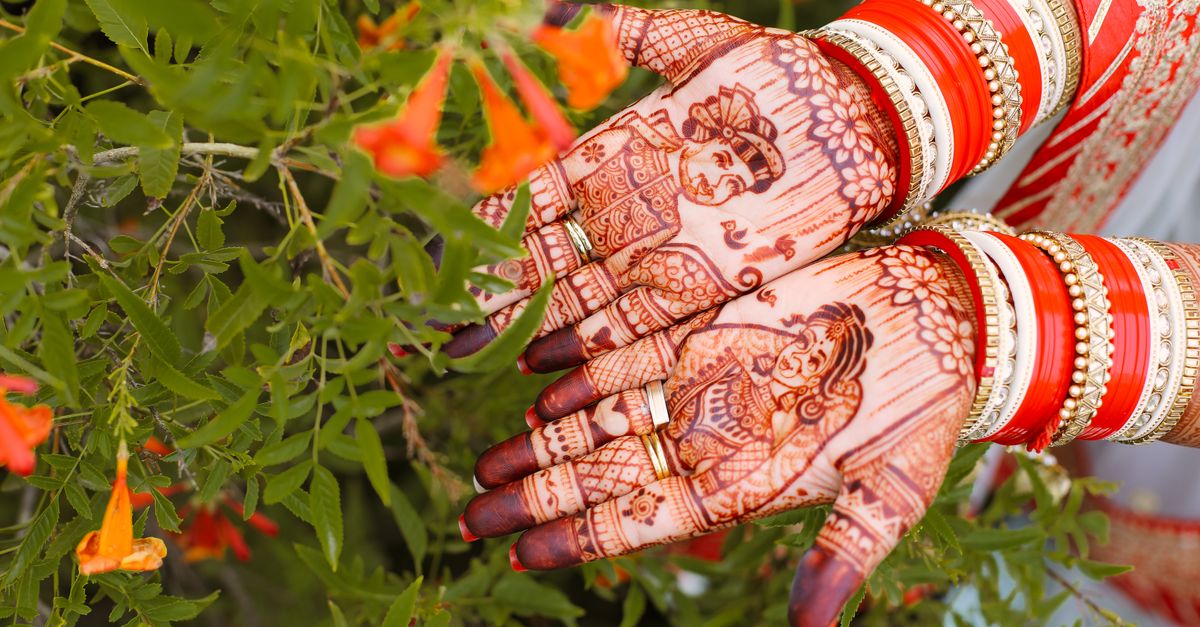 Henna being applied to a bride's hands before a Sikh wedding